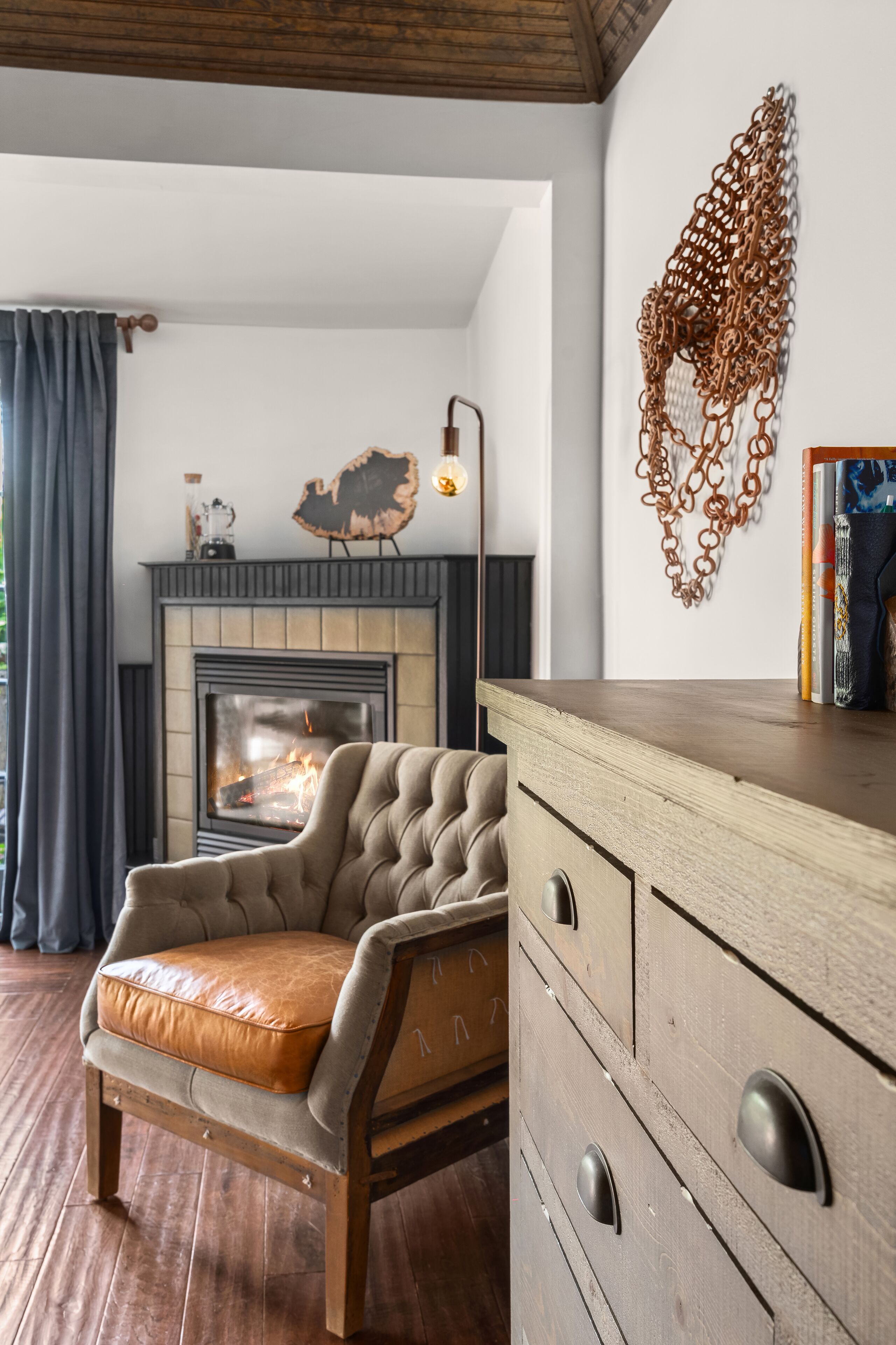 A living room with a fireplace, a wooden cabinet, and a decorative wall piece.