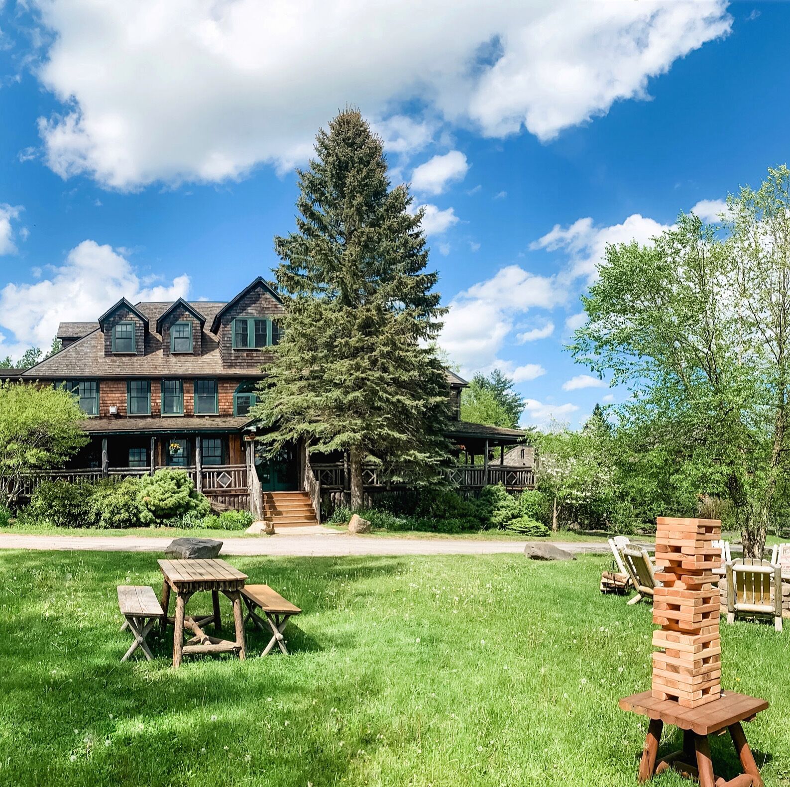 A large, rustic lodge with multiple stories and a prominent tree in front.