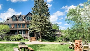 A large, rustic lodge with multiple stories and a prominent tree in front.
