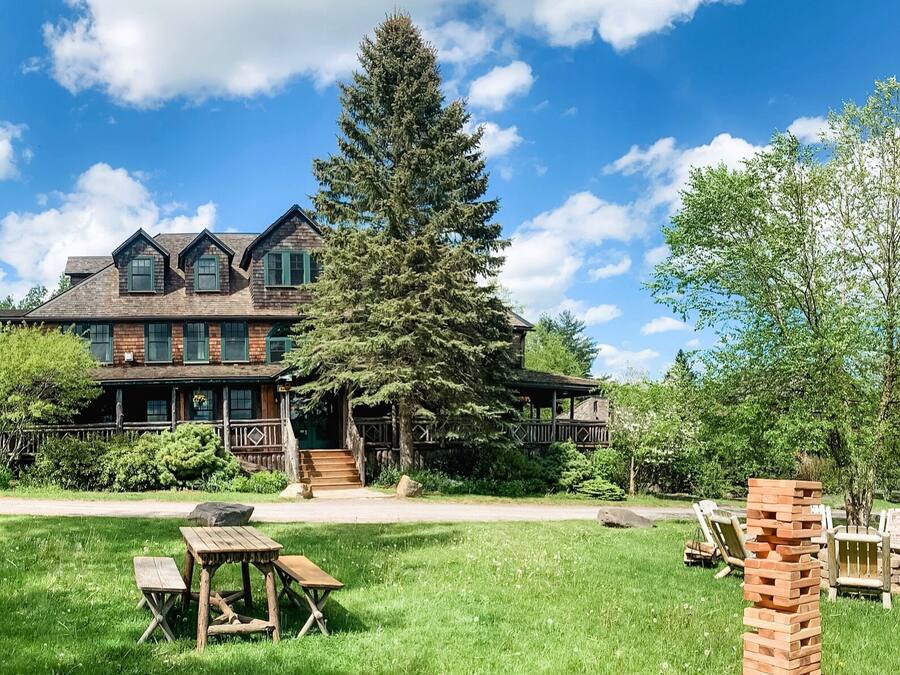 A large, rustic lodge with multiple stories and a prominent tree in front.