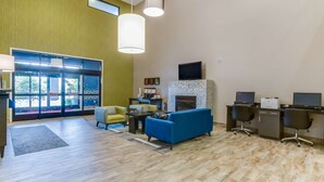 Una sala de estar moderna con chimenea, un sofá azul y un escritorio con computadoras.