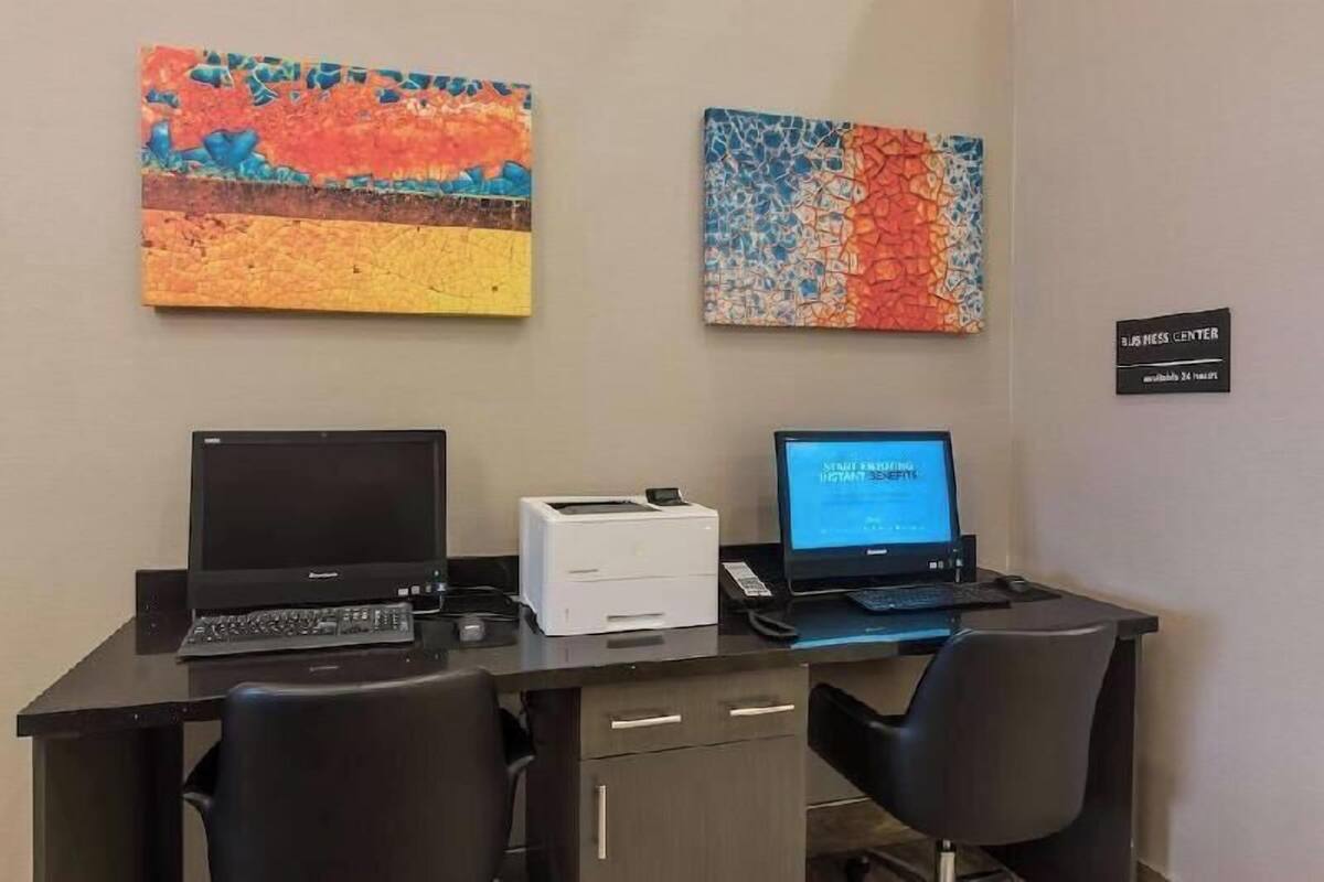 A workspace with two laptops, a printer, and two chairs.