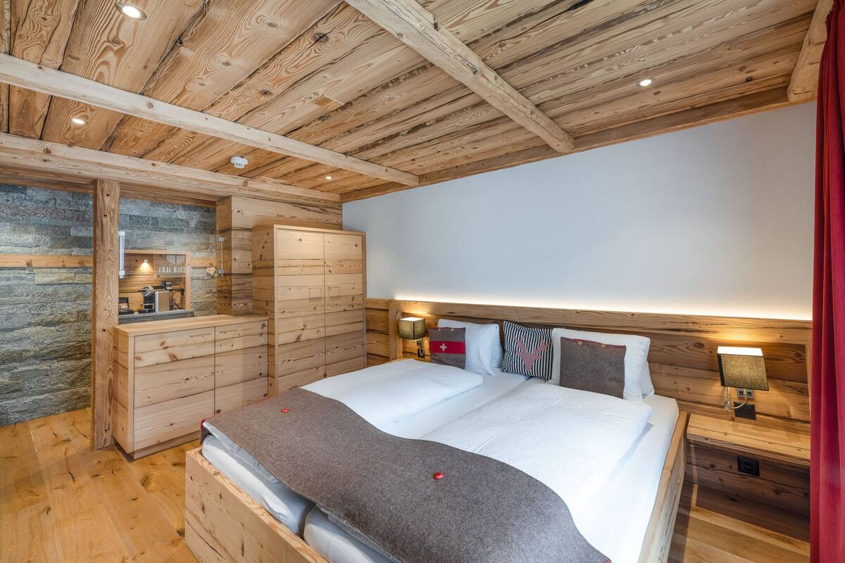 A wooden cabin bedroom with a bed, bedside tables, and a stone wall.