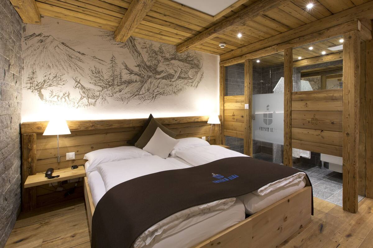 A wooden room with a bed, a nightstand, and a wall with a nature mural.