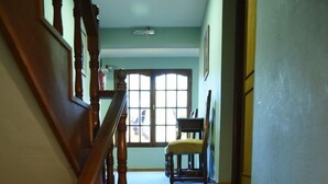 A staircase with a wooden handrail and carpeted steps leading to a landing with a chair and a window.