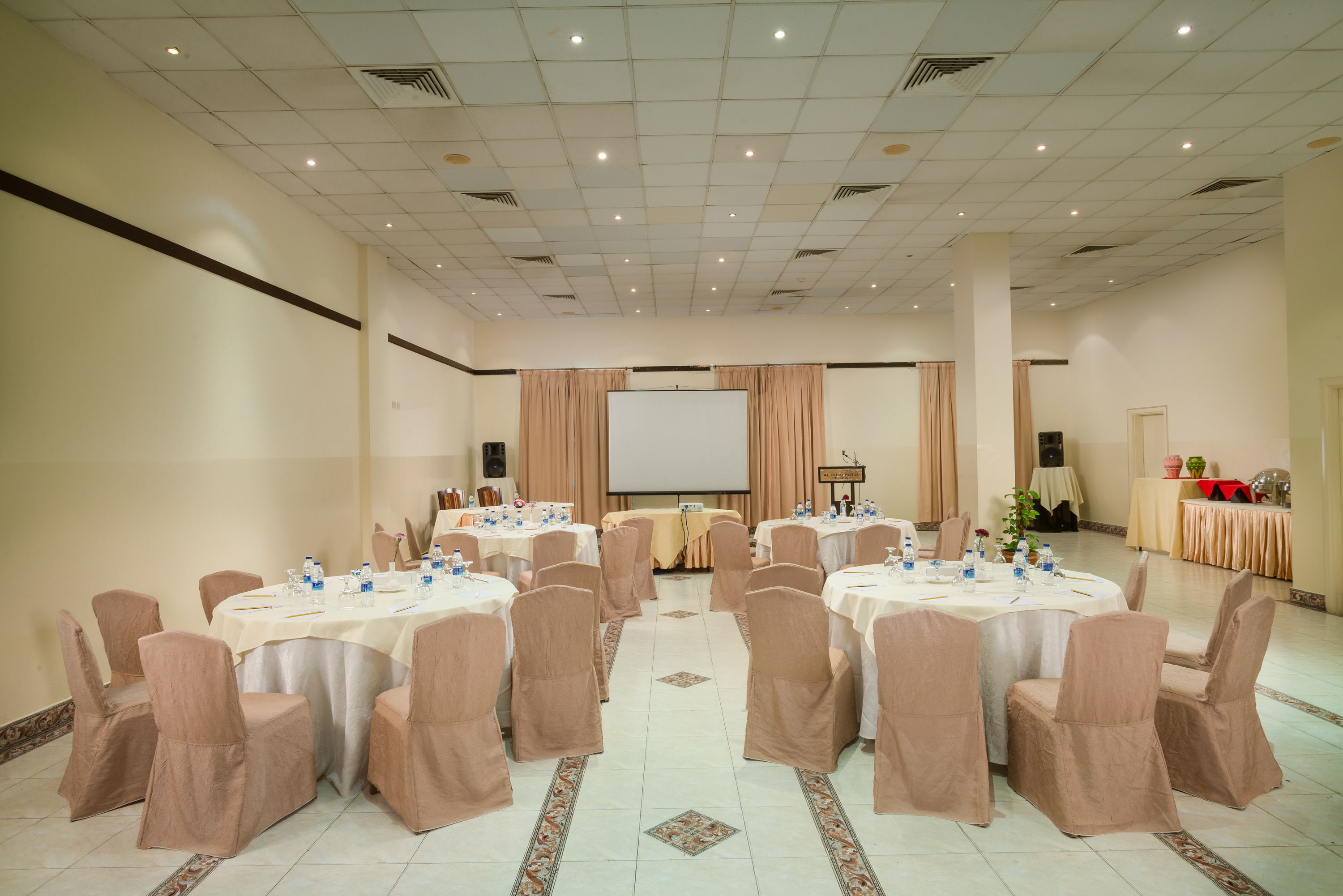 A conference room with round tables, chairs, and a projection screen.
