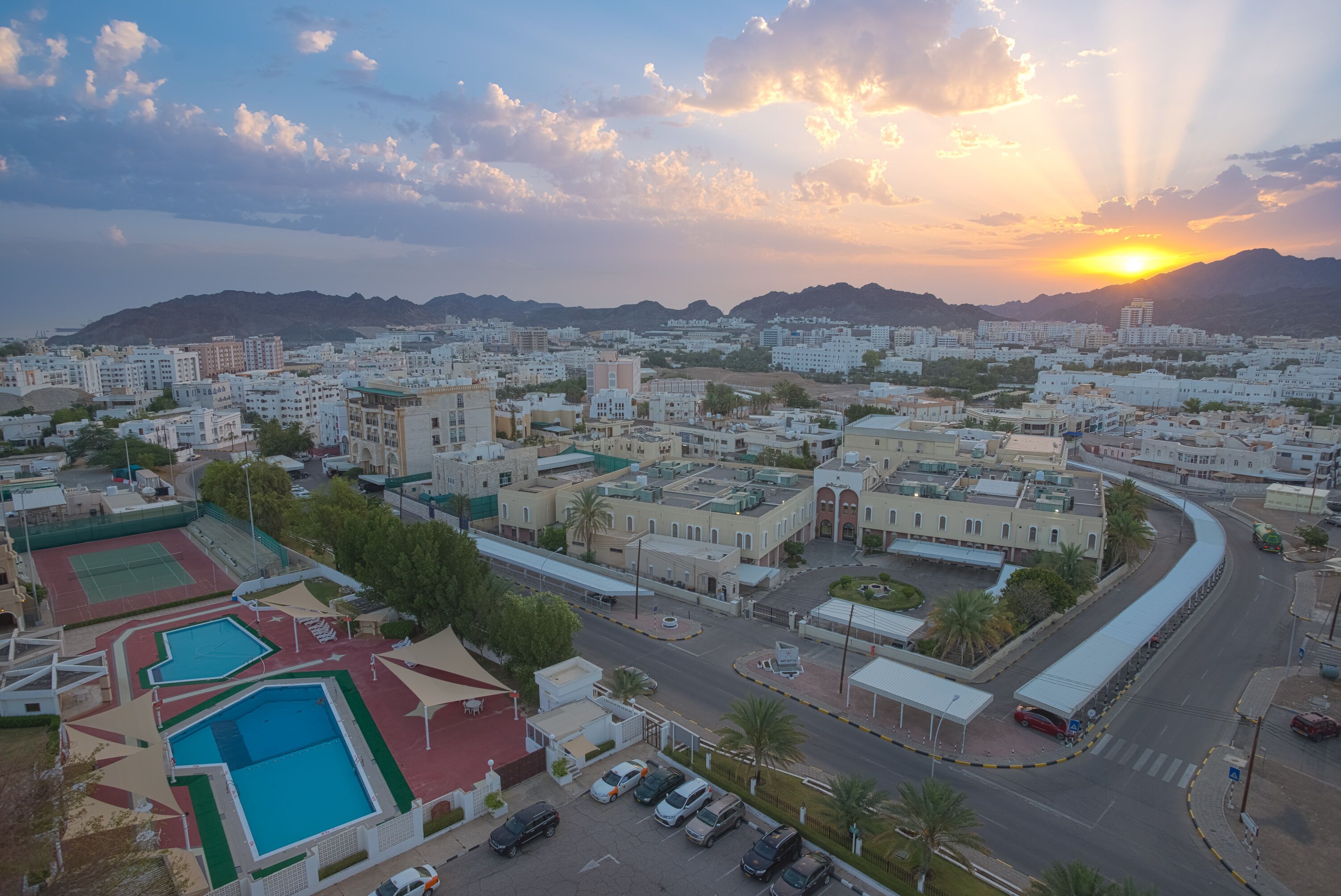 A cityscape with a large building complex, a swimming pool area, and a curved road.