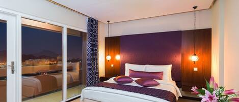 Quarto moderno com uma cama grande, vista para o horizonte urbano através de uma porta de correr de vidro e um painel decorativo na parede.