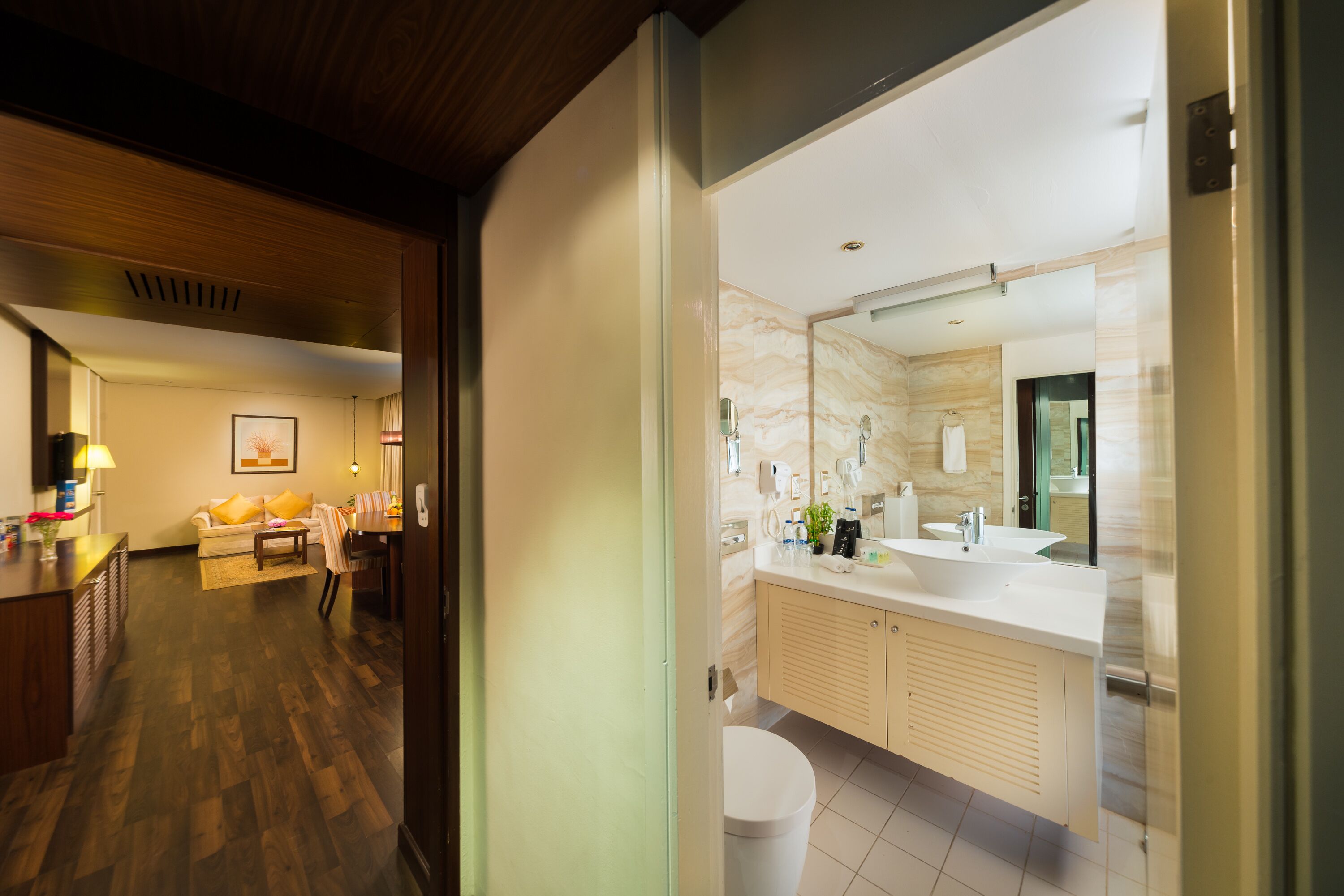 Un baño moderno con un espejo grande, un lavamanos blanco y armarios color beige.