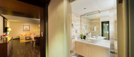 A modern bathroom with a large mirror, white sink, and beige cabinets.