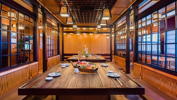 A traditional Japanese-style restaurant with wooden interiors, tatami flooring, and a central table with a fruit arrangement. - Al Falaj Hotel (Muscat)