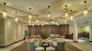 A spacious lobby with patterned sofas, a central coffee table, and hanging decorative lights. - Al Falaj Hotel (Muscat)