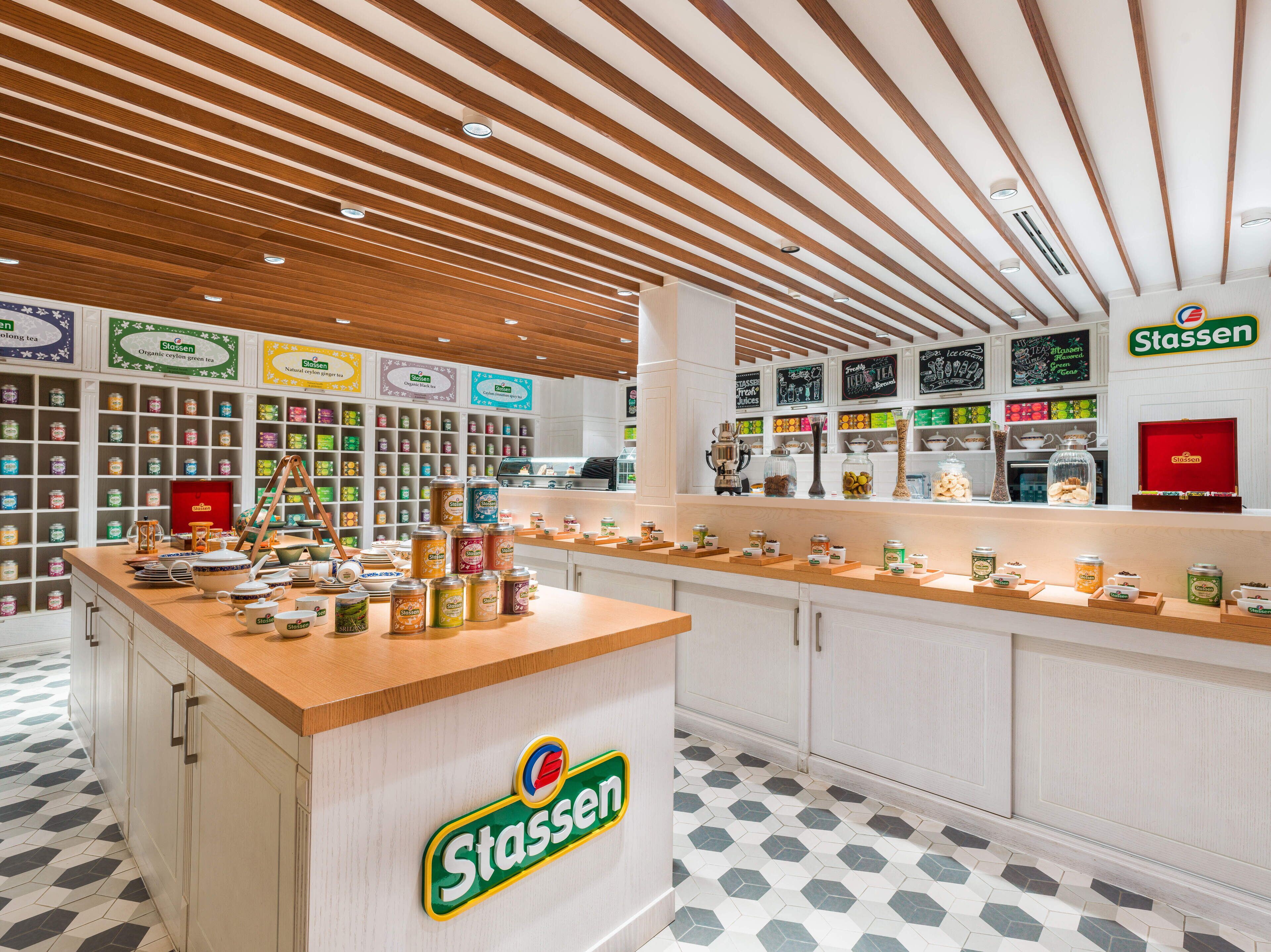 Una tienda de té Stassen con techo de madera, estanterías llenas de botes de té y un mostrador que exhibe productos de té.