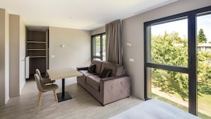 Une chambre d’hôtel moderne dotée d’une grande fenêtre, d’un canapé, d’une table et d’une armoire.