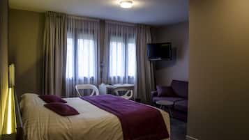 A hotel room with a bed, a desk, a chair, a television, and a couch.