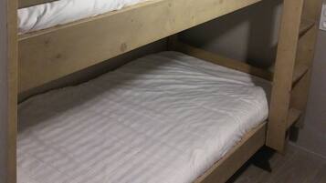 Una cama litera con dos niveles, cada uno con un colchón blanco.