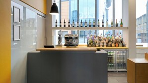 Zona de bar con una máquina de café, estantes con botellas y un refrigerador.