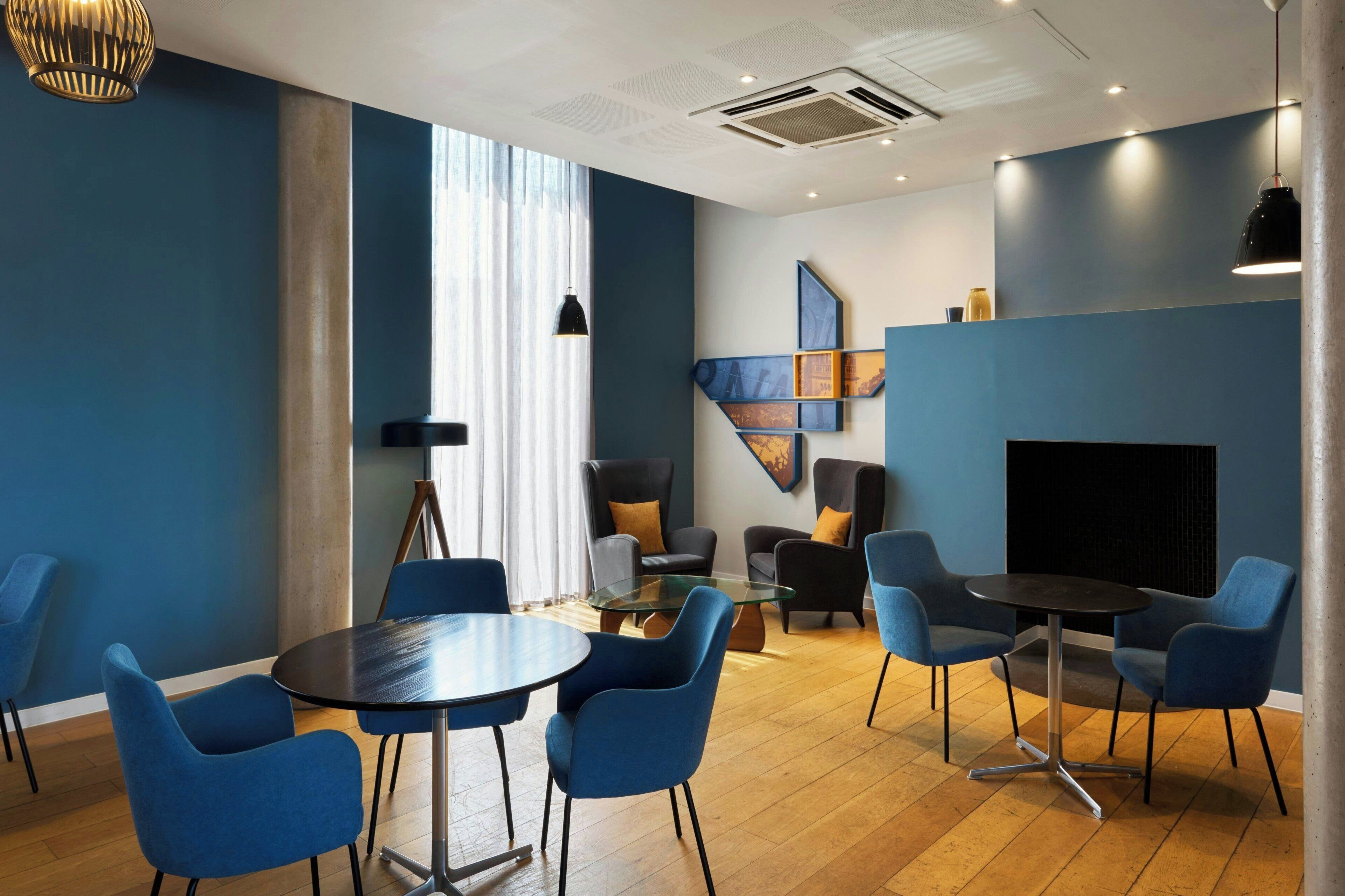A modern conference room with blue chairs, a glass table, and a black sofa.