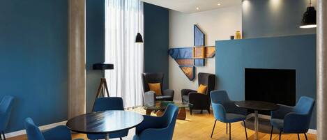 A modern conference room with blue chairs, a glass table, and a black sofa.
