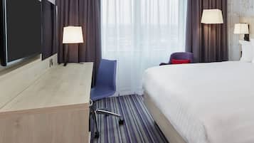 A hotel room with a bed, desk, chair, and two lamps.