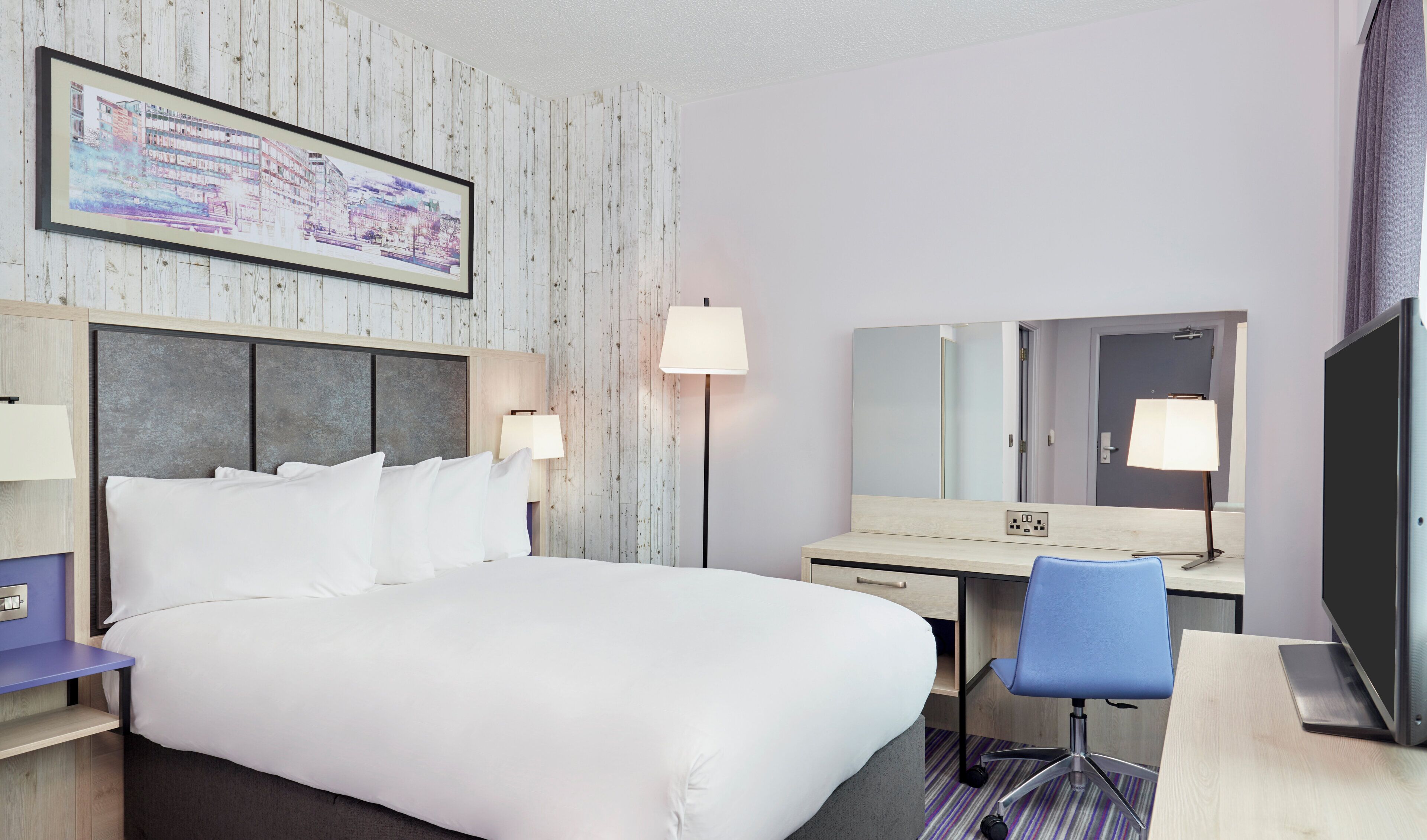 A hotel room with a large bed, a desk, a chair, a flat-screen TV, and a painting on the wall.