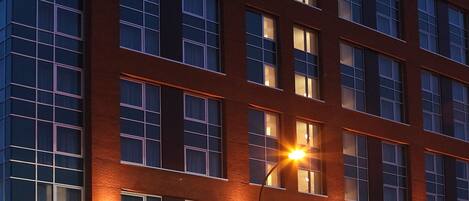 A modern building with multiple floors, large windows, and a brick facade.