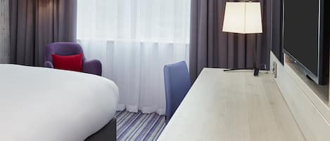 Een hotelkamer met een bed, twee stoelen, een bureau en twee lampen.