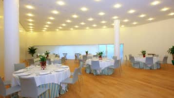 Amplia habitación con varias mesas redondas dispuestas para comer, cada una con sillas y centros de mesa.