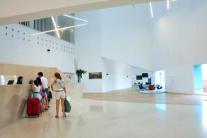 A spacious lobby with a modern design, a reception desk, and a seating area with chairs. - Hotel Hiberus (Zaragoza)