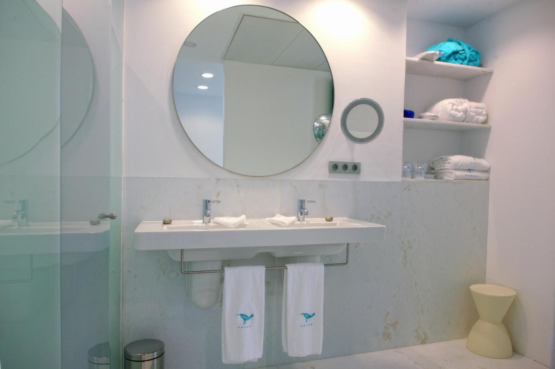 Un baño con lavamanos doble, un espejo grande, un perchero y un estante con toallas.