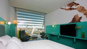 Un hotel moderno con una cama grande, un escritorio con una silla, un televisor y una ventana con vistas a un puente.