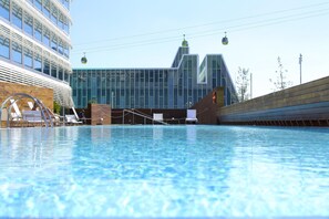 A swimming pool with lounge chairs and a modern building in the background. - Hotel Hiberus (Zaragoza)