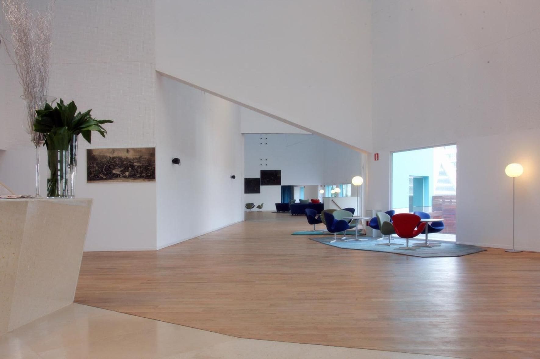 Un hall amplio con suelo de madera, asientos modernos y un ventanal grande.