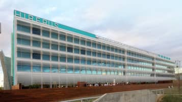 A modern building with the name "HIREBUS" on the facade, featuring a series of windows and a wooden deck area in front.