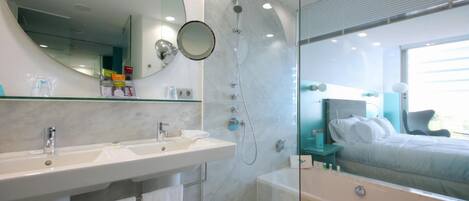 A modern bathroom with a large mirror, two sinks, a shower, and a bathtub.