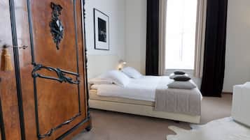 Classic hotel room with a large wardrobe, comfortable bed, and a bedside table with a lamp.