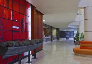 Un hall d’entrée spacieux avec un mur rouge, un coin salon et un design moderne.