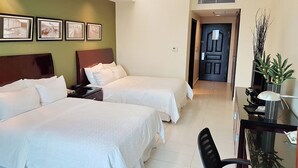 A hotel room with two beds, a desk, a chair, a TV, and a door leading to another room. - Sand Diamond Hotel (Colon)