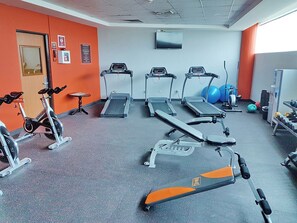 Une salle de sport équipée de tapis de course, d’un vélo d’appartement et de ballons d’exercice.
