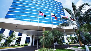 A modern hotel with a curved facade, multiple flags, and palm trees. - Sand Diamond Hotel (Colon)