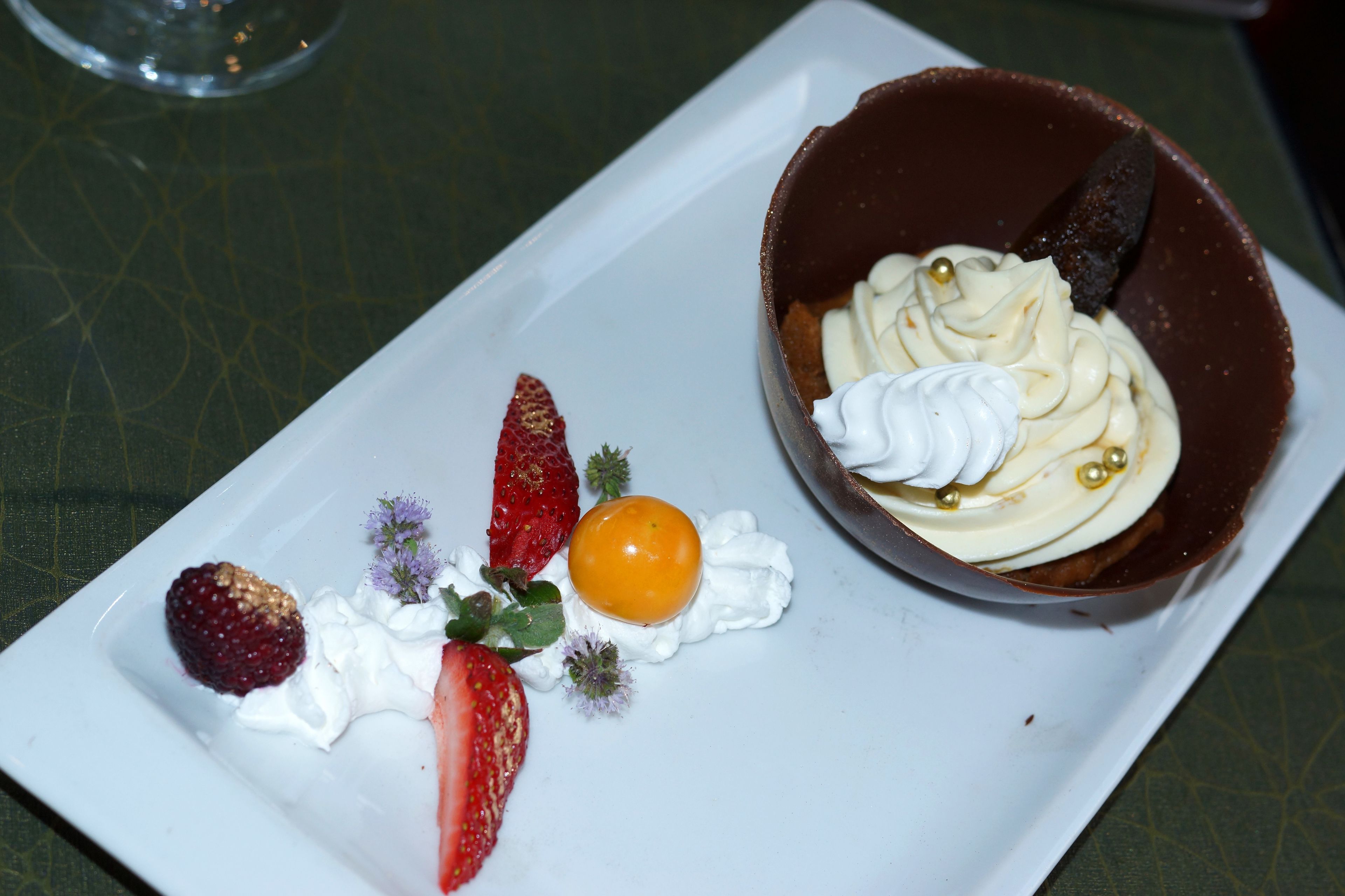 A dessert plate with a chocolate tart, strawberries, raspberries, and a small orange.