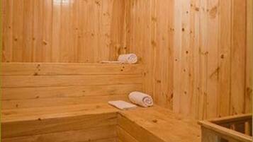 A wooden sauna with benches and a small seating area.