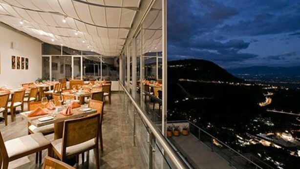 Ein Restaurant mit Terrasse und Blick auf eine nächtliche Stadtlandschaft.