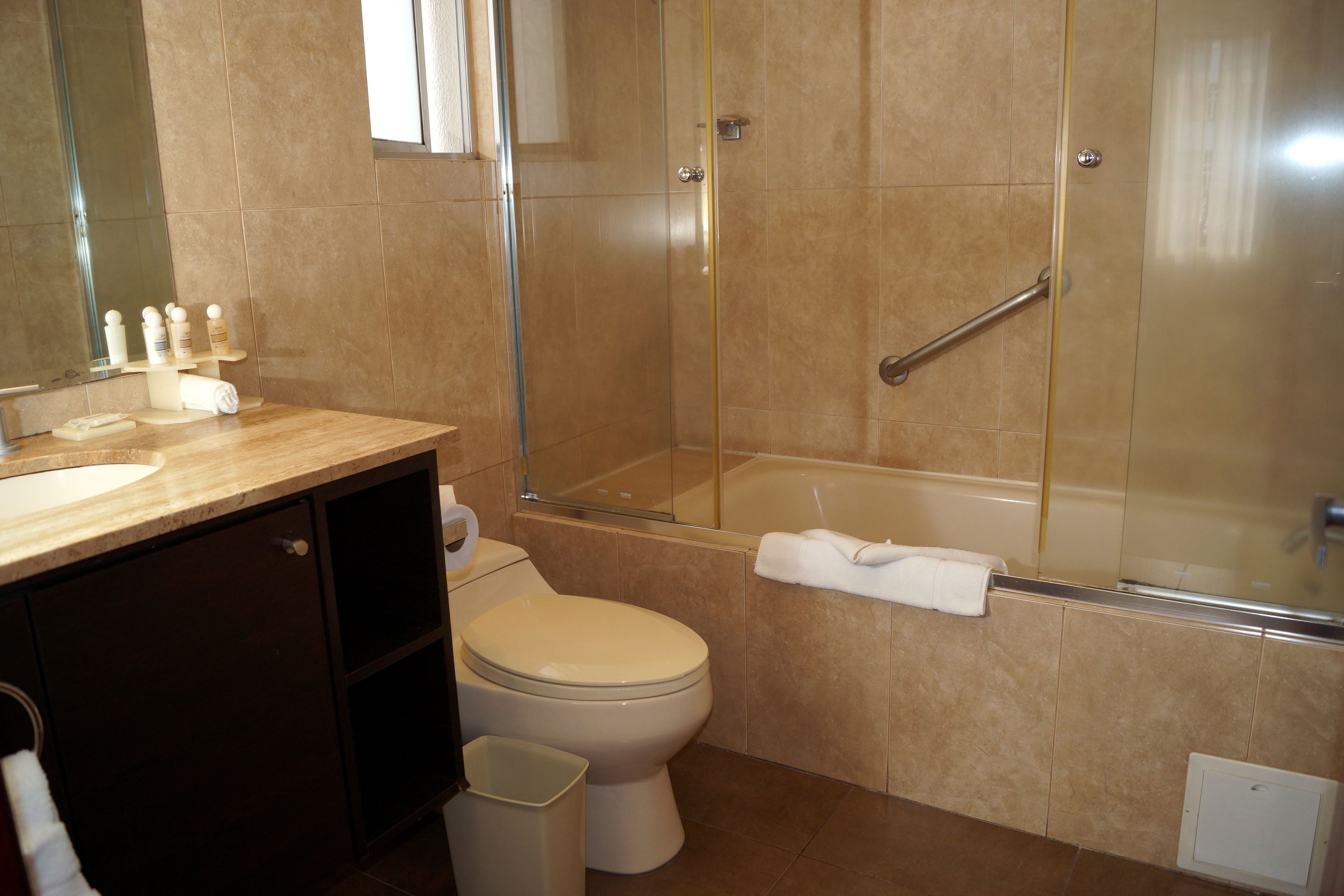 Une salle de bain moderne comprenant des toilettes, un lavabo et une douche séparée par des parois en verre.