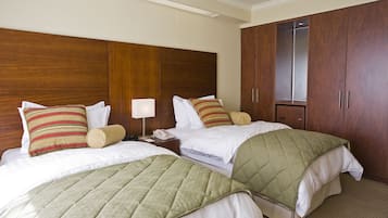 A hotel room with two beds, wooden headboards, and a wardrobe.