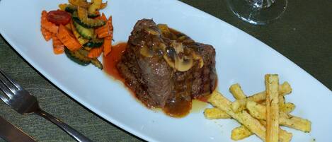 Une assiette de nourriture comprenant un steak, des légumes et des frites.