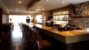 Eine Bar mit einer langen Theke, verschiedenen Sitzgelegenheiten und einer Weinauslage.
