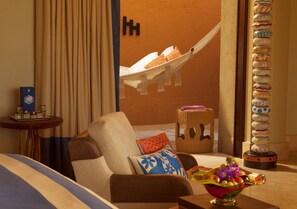 Ein Zimmer mit einer Hängematte, einem Korbwägelchen, einer Obstschale und einer Zierensäule.