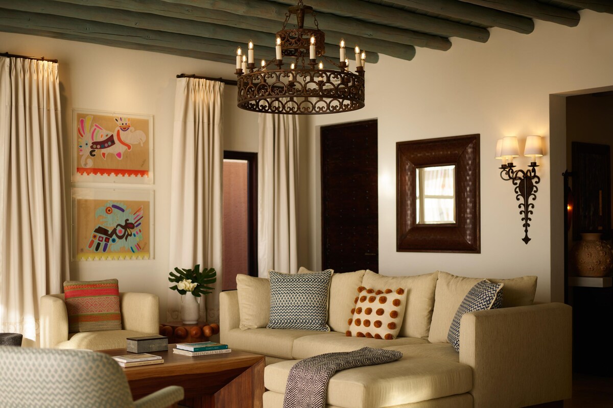 Ein gemütliches Wohnzimmer mit einem beigefarbenen Sofa, einem Holztisch und einer dekorativen Chandelier.