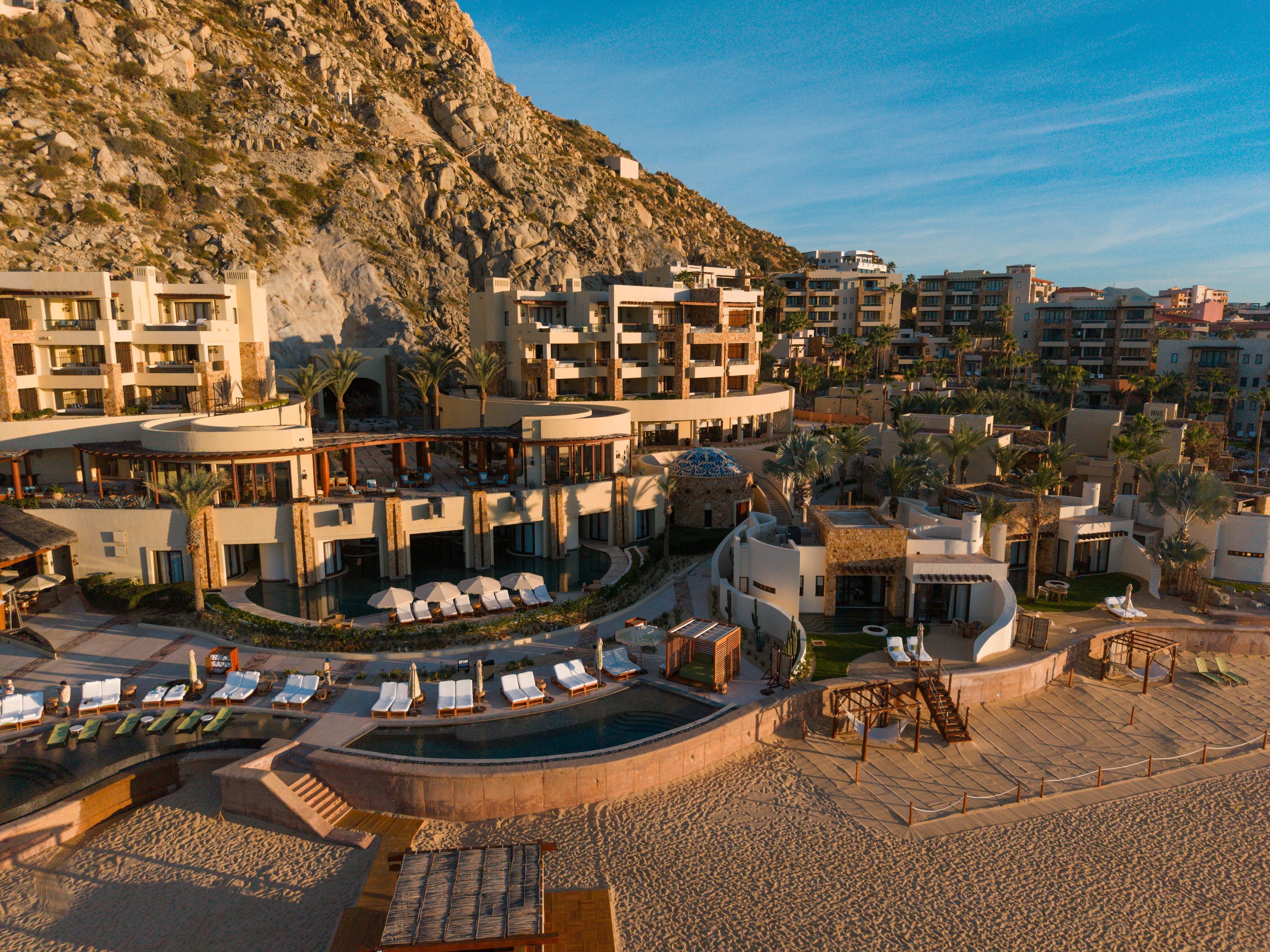 A resort with multiple buildings, a swimming pool, and a beach area.